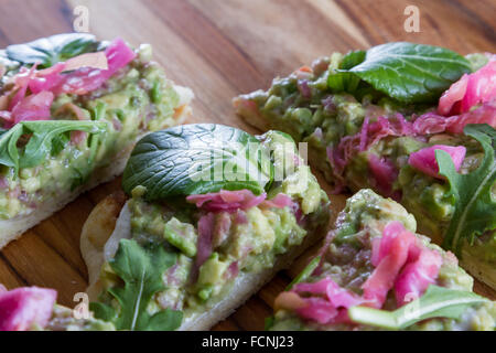 In prossimità di una fetta biscottata di pane piatto condito con una casa fatta diffondere utilizzando avocado e cavolo fermentato e poi rabboccato wit Foto Stock