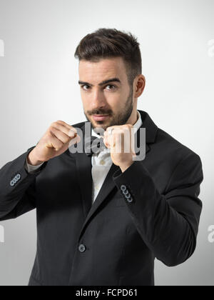 Nuovo fiero groom gesticolando pugno chiuso con anello di nozze. Ritratto su grigio di sfondo per studio. Foto Stock