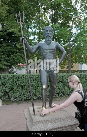 Un visitatore sfrega contro il piede del 'fortunato' statua di Nettuno in motivi di Peterhof Palace, Petergof, San Pietroburgo, Russia. Foto Stock