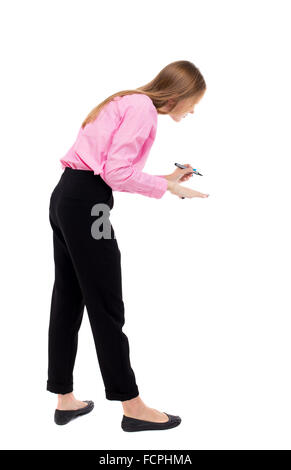 Vista posteriore della scrittura bella donna. Vista posteriore di raccolta persone. vista posteriore di persona. Isolato su sfondo bianco. Donna lavoratore di ufficio in una maglia rosa dipinge una penna con punta a feltro davanti a lui. Foto Stock