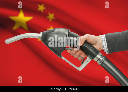 Pompa carburante ugello in mano con bandiera su sfondo - Cina Foto Stock