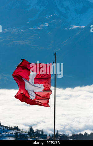 La bandiera svizzera è volare nel vento al di sopra delle nuvole sulla cima del Monte Rigi, la Svizzera centrale. Foto Stock