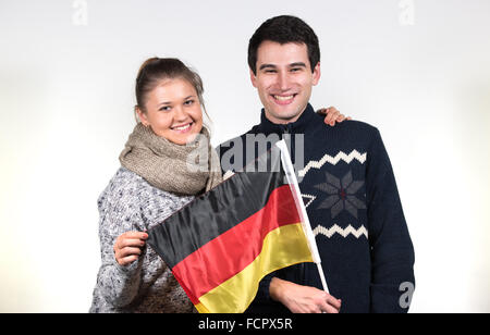 Ritratti di coppia giovane, uomo e donna, indossare abbigliamento invernale, tenendo bandiera tedesca Foto Stock