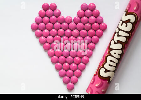 Nestle Smarties rosa disposti a forma di cuore con il set di tubi su sfondo bianco - Pronto per il giorno di San Valentino, il giorno di San Valentino Foto Stock