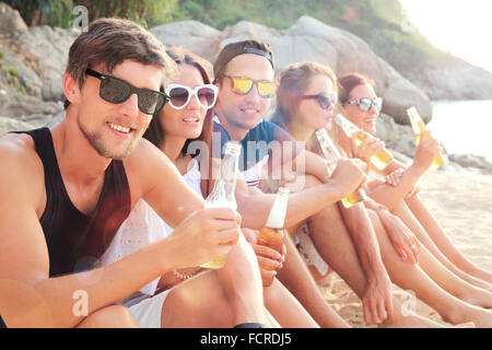 Felice giovani amici a bere birra sulla spiaggia Foto Stock