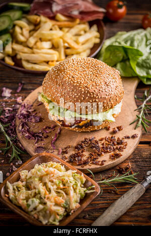 Burger servito con patate fritte e insalata mista Foto Stock