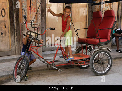 Bambini che giocano su taxi bicicletta, Habana Vieja (l'Avana Vecchia), Cuba Foto Stock