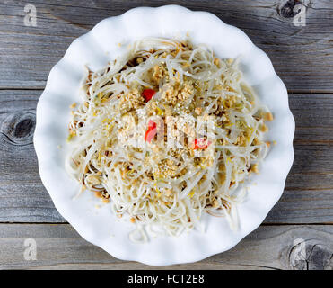 Alta vista ad angolo del piatto asiatico consistente di tagliatelle, germogli di bambù, peperoni e i semi di sesamo su legno rustico. Foto Stock