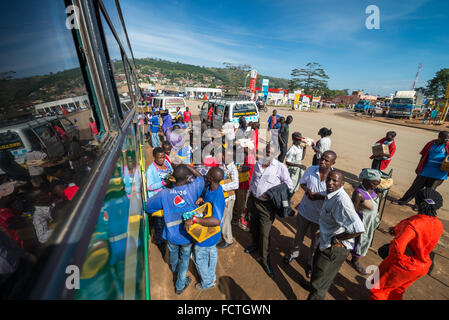 Venditori ambulanti vendono beni alle persone su bus locali passando attraverso i villaggi sulla strada fuori da Kampala, Uganda, Africa Foto Stock