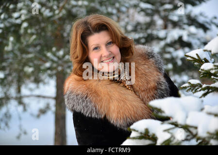 Positivo di mezza età della donna nella foresta di inverno Foto Stock