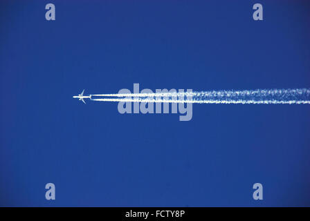 Un aereo lascia una lunga scia nel cielo blu. Foto Stock