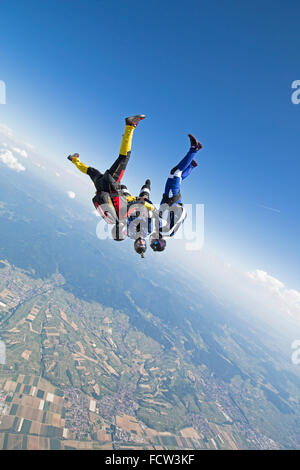 Questo freefly skydiving team sta tenendo la mano in posizione a testa in giù. In tal modo essi rush con una velocità superiore di 150 mph giù insieme! Foto Stock