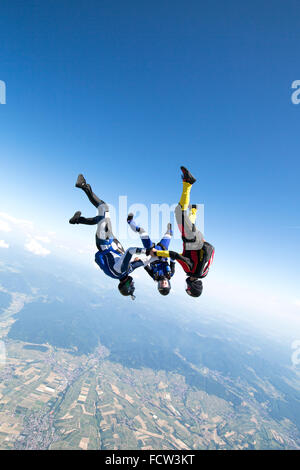 Questo freefly skydiving team è tenuta insieme a mano in posizione a testa in giù. In tal modo essi rush con una velocità superiore di 150 mph in giù! Foto Stock