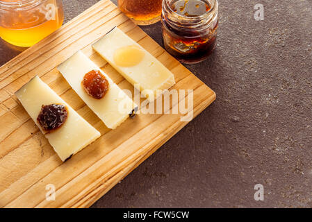 Una composizione di formaggi italiani pecorino fette con marmellate di sapori diversi su un tagliere di legno Foto Stock