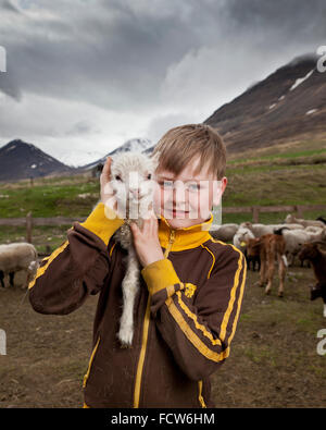 Ragazzo con agnello neonato, Audbrekka farm, Horgardalur valley, Islanda Foto Stock