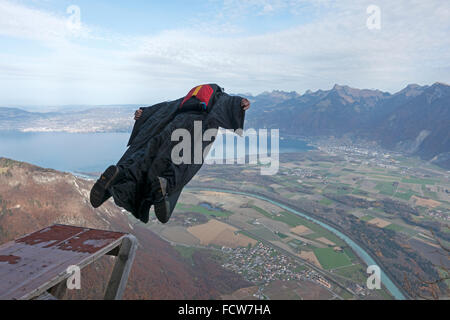 Questo wingsuit ponticello di base appena usciti da un trampolino verso il basso nella valle. Egli aprirà il suo paracadute appena prima il terreno. Foto Stock