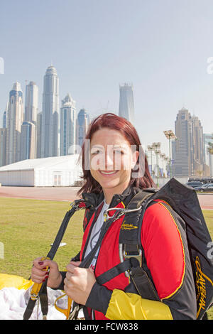 Questa ragazza paracadutista è molto felice che ha atterrato salvare sull'erba dedicata area sulla airfield, dopo un salto sopra Dubai Palm. Foto Stock