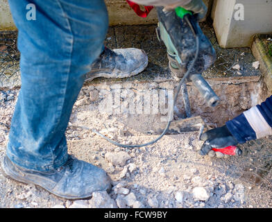 Sito in costruzione - lavoratori utilizzando Jackhammer e cazzuola di eseguire la traccia sul piano marciapiede messa a fuoco selettiva e la sfocatura in movimento Foto Stock