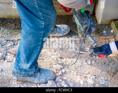 Sito in costruzione - lavoratori utilizzando Jackhammer e cazzuola di eseguire la traccia sul piano marciapiede messa a fuoco selettiva e la sfocatura in movimento Foto Stock