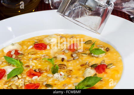 Una zuppa di riso con i semi di zucca, i cereali e i pomodori in una ciotola bianco. Foto Stock