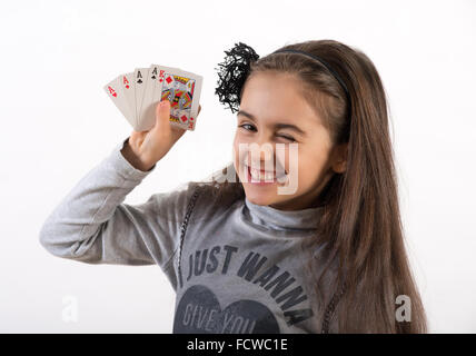 Lucky graziosa bambina occhiolino alla telecamera come ella mostra la sua mano di poker di 4 assi e un re Foto Stock