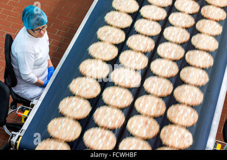 Wittenburg, Germania. 08 Dic, 2015. Un dipendente supervisiona l'aggiunta di condimenti per pizze surgelate in corrispondenza di una linea di produzione della pizza impianto del produttore di alimenti Dr. Oetker a Wittenburg, Germania, 08 dicembre 2015. In base alle proprie informazioni, la società con i suoi 900 dipendenti è uno dei più grandi datori di lavoro dello Stato tedesco Meclemburgo-Pomerania occidentale. Foto: Jens BUETTNER/dpa/Alamy Live News Foto Stock