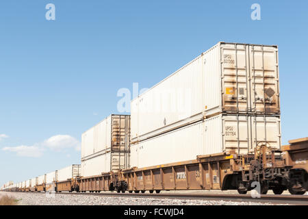 Treno carico di contenitori di merci rotoli anche se nuovo Messico di alta pianura paesaggi e dalla ferrovia a fianco di Route 66 punto di messa a fuoco Foto Stock