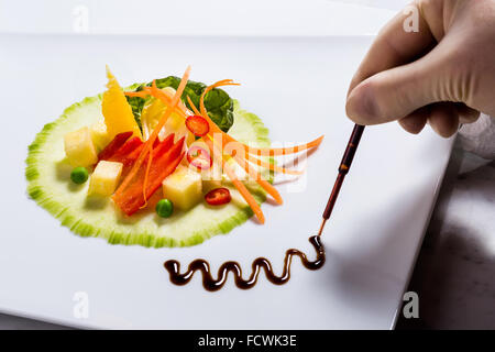 Creazione di insalata insalata Fitness guarnire con la pipetta, balsamico via, plastica, fatta a mano, deco con mano, cuocere la cottura salateria fr Foto Stock