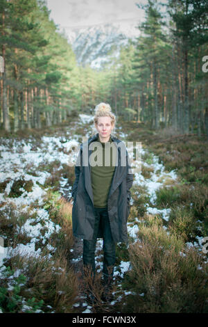 Una donna a piedi attraverso una foresta Foto Stock