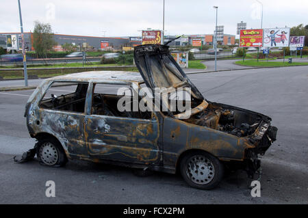 Un bruciato auto abbandonate in un fuori città retail estate a fianco del N20 autostrada del sud di Parigi. La Francia. Foto Stock