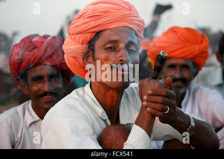 Rajasthani driver cammello chillum fumatori, con turban arancione , in Pushkar, rajasthan Foto Stock