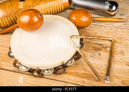 Tradizionale piccola p'ercussion strumenti in una vita ancora su un rustico di una superficie di legno Foto Stock