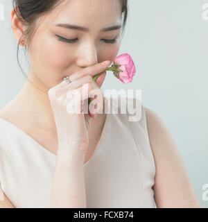 Donna odorare una rosa con gli occhi chiusi Foto Stock