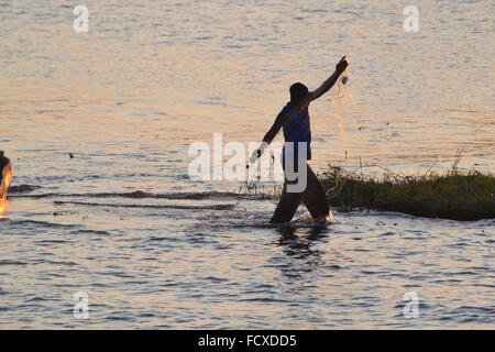 Pescatore al tramonto sul fiume Chobe tra Botswana e Namibia, Africa Foto Stock