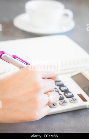 Mano che tiene la penna e premendo i pulsanti di calcolatrice, stock photo Foto Stock