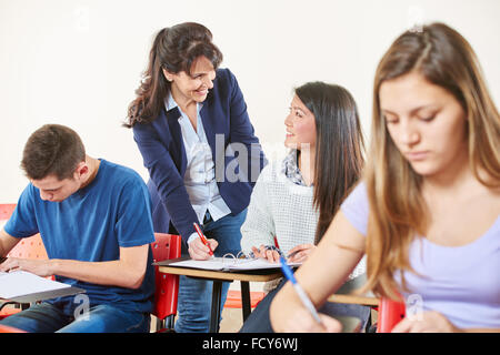 Insegnante aiuta un alunno durante un test e sorrisi Foto Stock