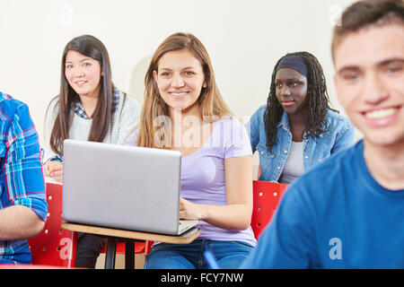 Ragazza apprende con il computer portatile in classe con il suo interracial compagni di classe Foto Stock
