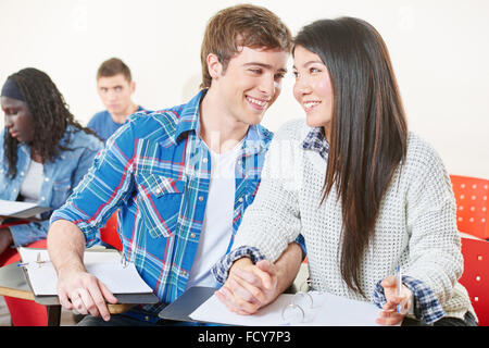 Ragazzini in amore tenendo le mani durante la classe al liceo Foto Stock