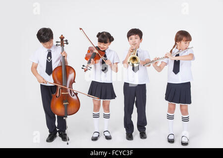 Quattro gli studenti della scuola elementare in uniformi di scuola permanente e la riproduzione di musica classica strumento ciascuno Foto Stock