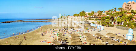 TENERIFE, Spagna - 14 gennaio 2013: la spiaggia di sabbia fine attrezzata con ombrelloni di paglia e lettini, Costa Adeje, Tenerife, Isole Canarie, Spagna Foto Stock