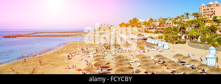 TENERIFE, Spagna - 14 gennaio 2013: la spiaggia di sabbia fine attrezzata con ombrelloni di paglia e lettini, Costa Adeje, Tenerife, Isole Canarie, Spagna Foto Stock