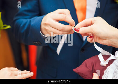 Lo sposo mettendo ad anello sulla sposa del dito Foto Stock