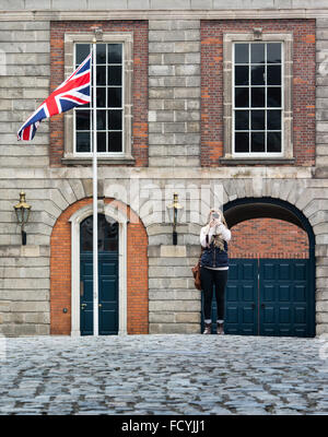 Turistica prendendo le foto nel cortile del Castello di Dublino in Irlanda con la britannica Union Jack battenti in background. Foto Stock