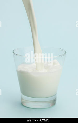 Il latte che viene versato in un bicchiere Foto Stock
