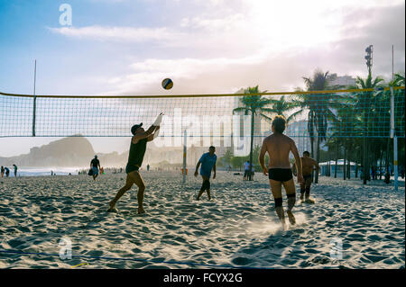 RIO DE JANEIRO - 30 ottobre 2015: un gruppo di giovani uomini brasiliano di giocare una partita di pallavolo al tramonto al Leme, Copacabana. Foto Stock