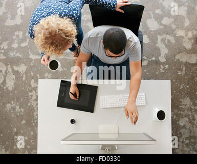 Vista dall'alto di giovani graphic designer che lavorano in ufficio. Utilizzando digitalizzato tavoletta grafica, digitalizzato la penna e il computer desktop. L uomo s Foto Stock