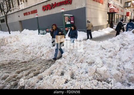 Pedoni slog attraverso pozzanghere di granite e neve mentre si recano al lavoro al mattino in corrispondenza di incroci stradali con neve dam intasato Tempesta fognature nel quartiere di Chelsea di New York lunedì, 25 gennaio 2016. Tempesta di neve Jonas oggetto di dumping 26,8 pollici su Central Park rendendo la seconda maggiore quantità poiché i record è iniziato nel 1869 e con temperature che salgono sopra il congelamento di alcuni che la neve si fonde. (© Richard B. Levine) Foto Stock