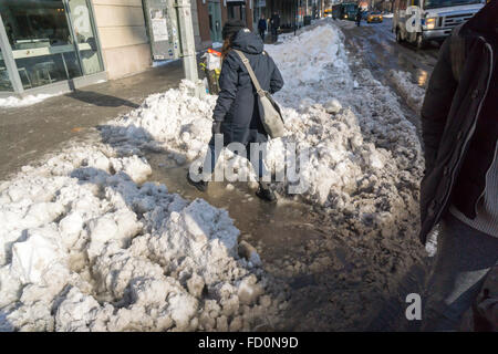 Pedoni slog attraverso pozzanghere di granite e neve mentre si recano al lavoro al mattino in corrispondenza di incroci stradali con neve dam intasato Tempesta fognature nel quartiere di Chelsea di New York lunedì, 25 gennaio 2016. Tempesta di neve Jonas oggetto di dumping 26,8 pollici su Central Park rendendo la seconda maggiore quantità poiché i record è iniziato nel 1869 e con temperature che salgono sopra il congelamento di alcuni che la neve si fonde. (© Richard B. Levine) Foto Stock