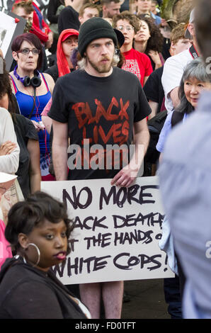 Un dimostrante in corrispondenza di 2015 giorno di maggio nel rally di Portland, Oregon detiene un segno protesta morti nero Foto Stock