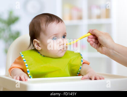 Madre alimenta funny baby da un cucchiaio Foto Stock